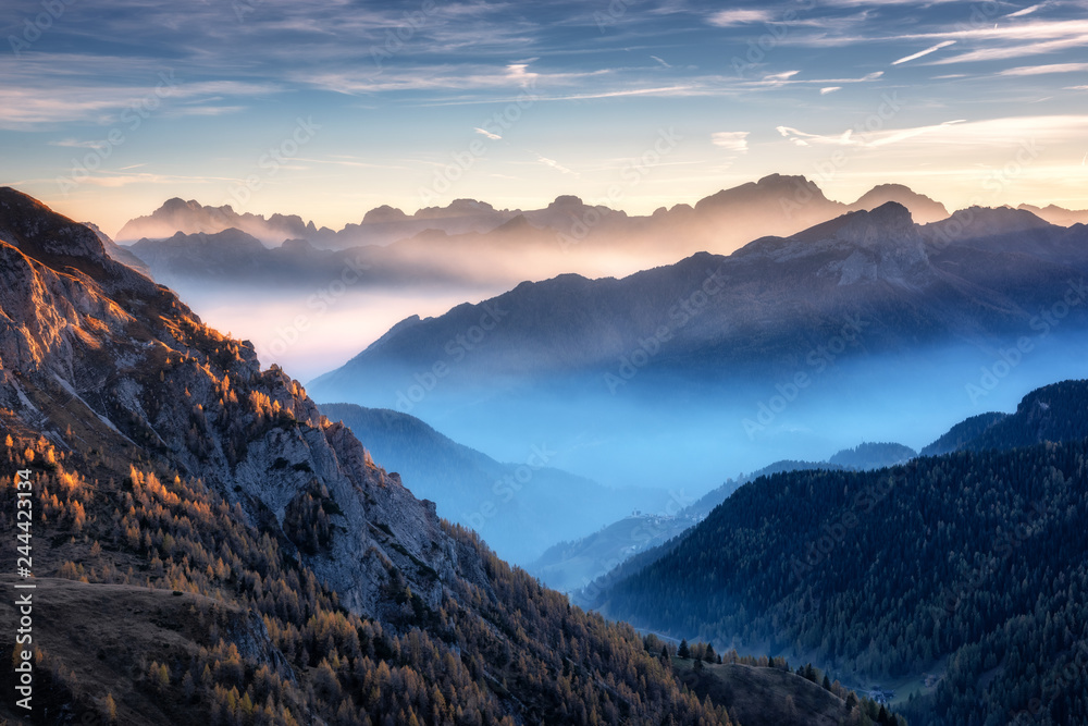 Mountains in fog at beautiful sunset in autumn in Dolomites, Italy. Landscape with alpine ...