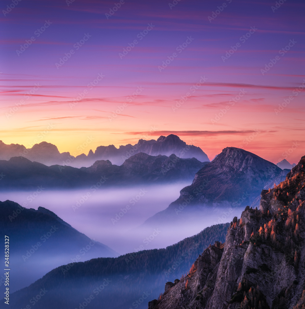 Mountains in fog at beautiful sunset in autumn in Dolomites, Italy. Landscape with alpine ...