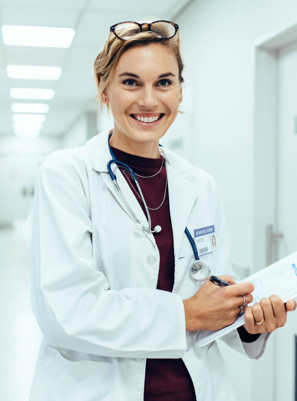 Patient-finance-Happy-young-female-doctor-standing-in-hospital Corridor - CURAE, Financial...