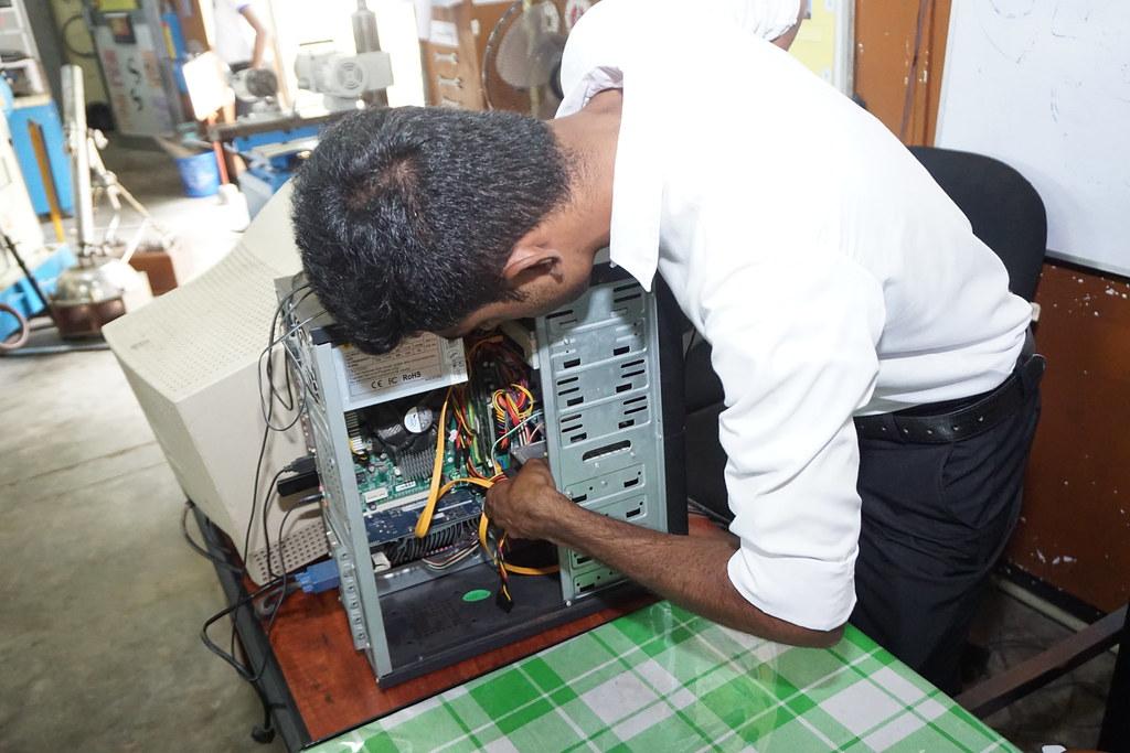 a man in a white shirt is working on a computer – Hardware technician | Genesage